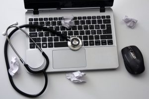 A healthcare professional's stethescope on top of a laptop keyboard.