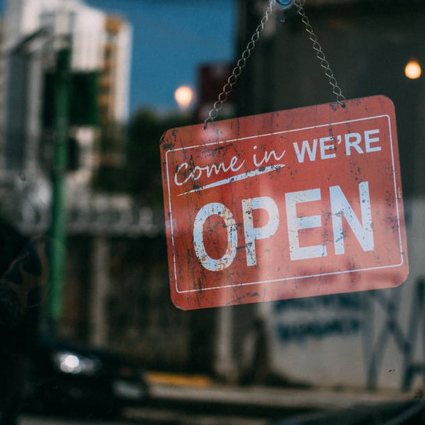 A sign reading, "Come in, we're open," posted in the window of a small business.